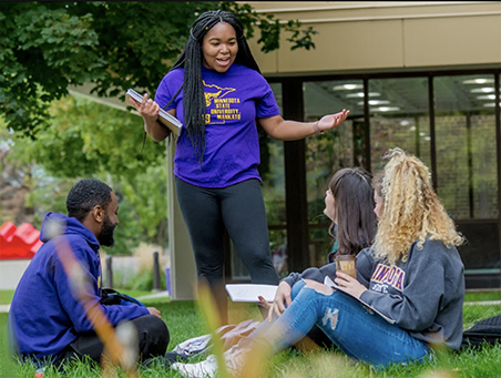 Diversity photo of students engaged in conversation on the campus lawn.